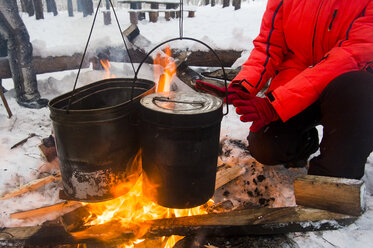 Beschnittene Ansicht einer Frau, die sich die Hände am Lagerfeuer wärmt, Russland - CUF10363