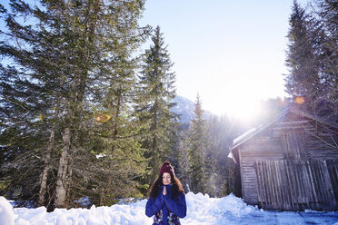 Frau praktiziert Yoga, meditiert im verschneiten, sonnenbeschienenen Wald, Österreich - CUF10370
