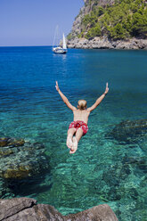 Rear view of young man diving into sea, Cala Tuent, Majorca, Spain - CUF10376