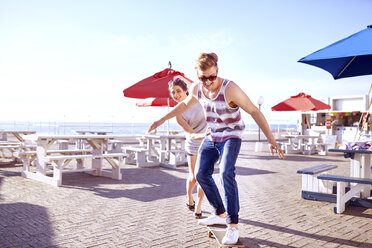 Couple using skateboard on promenade - CUF10383