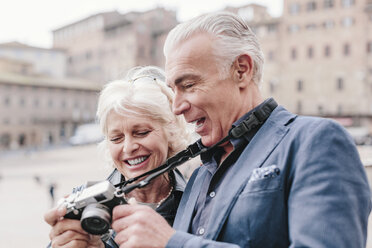 Touristenpaar beim Betrachten einer Digitalkamera auf dem Stadtplatz, Siena, Toskana, Italien - CUF10417