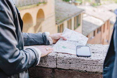 Ausgeschnittene Aufnahme eines Touristenpaars, das eine Landkarte an der Wand betrachtet, Siena, Toskana, Italien - CUF10422