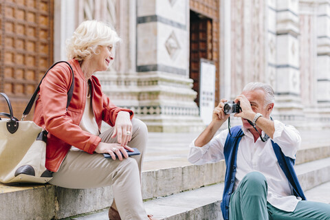 Senior male tourist photographing wife on Siena cathedral stairway, Tuscany, Italy stock photo