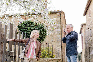 Männlicher Senior-Tourist fotografiert Frau und Blüte, Siena, Toskana, Italien - CUF10429