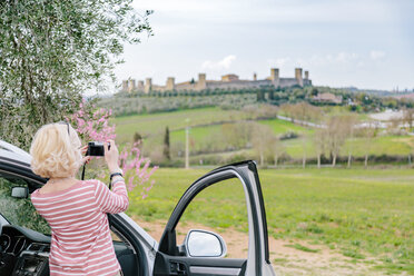 Rückansicht einer Touristin, die eine Festung in der Landschaft fotografiert, Siena, Toskana, Italien - CUF10432
