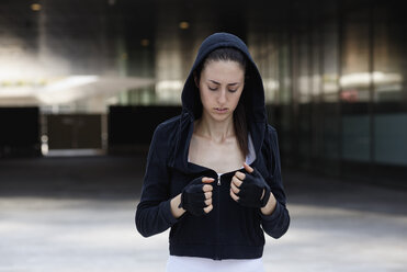 Young woman outdoors, wearing hooded top and fingerless gloves - CUF10476