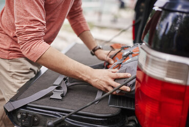 Beschnittene Ansicht eines Mannes, der seinen Rucksack in den Kofferraum eines Autos packt, Krakau, Malopolskie, Polen, Europa - CUF10511