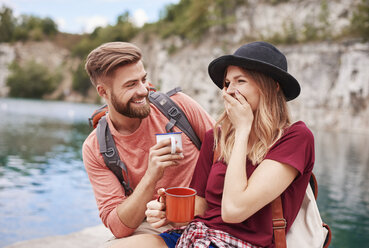 Couple by water holding enamel mugs smiling, Krakow, Malopolskie, Poland, Europe - CUF10519