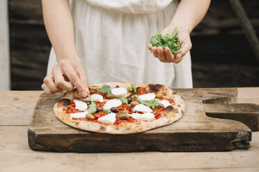 Frau belegt hausgemachte Pizza mit Kräutern, Mittelteil - CUF10531