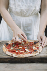 Frau belegt selbstgemachte Pizza mit Zutaten, Mittelteil - CUF10532