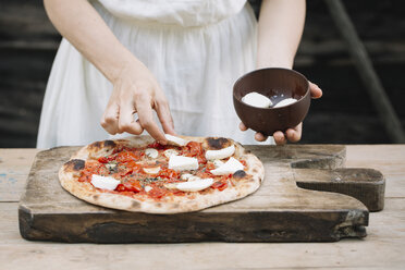 Frau, die Mozzarella auf selbstgemachte Pizza legt, Mittelteil - CUF10534