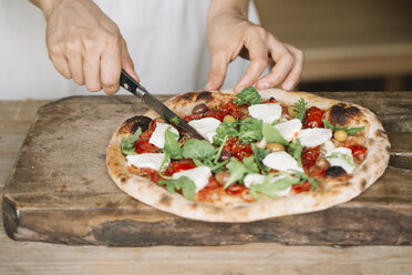 Frau schneidet hausgemachte Pizza auf einem Schneidebrett, Mittelteil - CUF10535