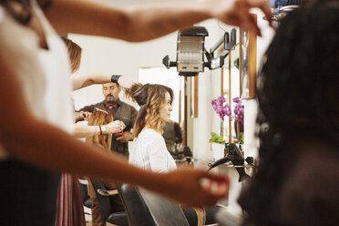 Weibliche Kunden lassen sich im Friseursalon die Haare stylen - CUF10554