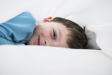 Porträt eines zwischen weißen Bettlaken liegenden Jungen - CUF10563