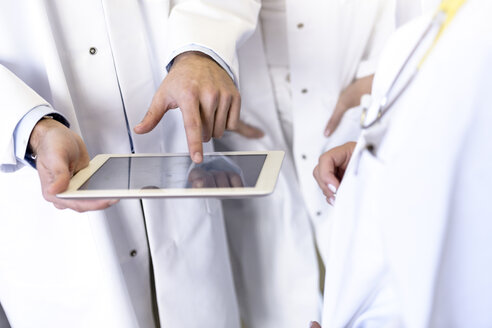 Mittelteil eines männlichen und eines weiblichen Arztes, die ein digitales Pad mit Touchscreen im Krankenhaus benutzen - CUF10584