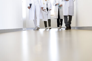 Blick von unten auf männliche und weibliche Ärzte, die in einem Krankenhauskorridor gehen - CUF10587