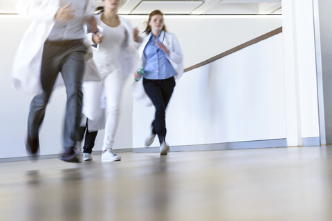 Männliche und weibliche Ärzte laufen den Krankenhausflur entlang, lizenzfreies Stockfoto