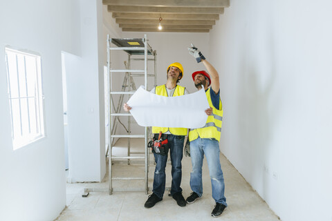 Two workers talking holding construction plan stock photo