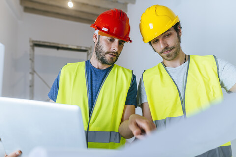 Workers working with laptop and plan on the construction site stock photo