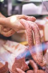 Female butcher holding sausage - AFVF00451