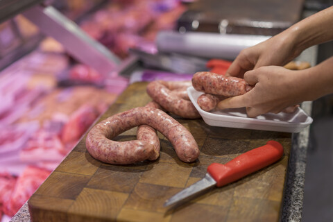 Female butcher cutting sausage stock photo