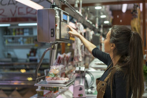 Metzgerin wiegt Wurst auf einer Waage - AFVF00463