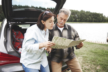 Mature couple in rural setting, standing beside car, looking at map - CUF10651