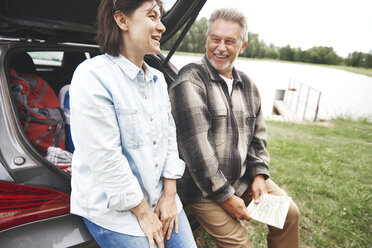 Älteres Paar in ländlicher Umgebung, neben dem Auto stehend, lachend - CUF10652