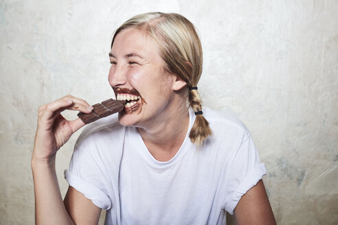 Frau isst eine Tafel Schokolade, Schokolade um den Mund, lachend - CUF10677