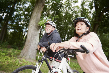 Älteres Paar, das auf einem ländlichen Weg mit Fahrrädern spazieren geht und die Aussicht genießt - CUF10682