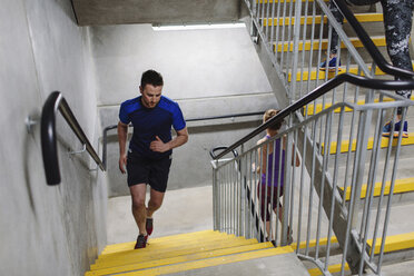 Young male runner running up indoor stairway - CUF10707