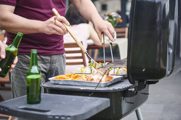 Mid section of man barbecuing on patio at family lunch - CUF10855