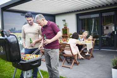 Reifer und mittelgroßer erwachsener Mann grillt beim Familienessen auf der Terrasse - CUF10864