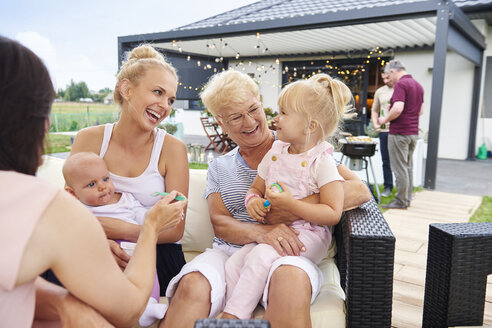 Frauen der dritten Generation mit Kindern auf dem Schoß beim Familienessen auf der Terrasse - CUF10866