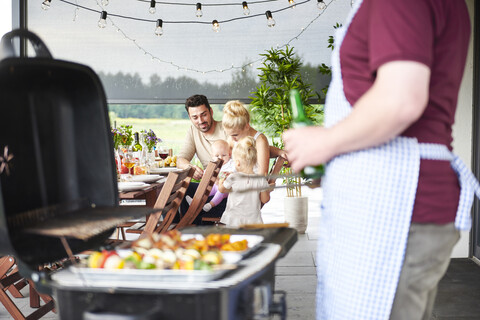 Mann grillt beim Familienessen auf der Veranda, lizenzfreies Stockfoto