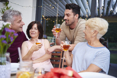 Eine erwachsene Familie unterhält sich und trinkt Wein zum Mittagessen auf der Terrasse - CUF10873