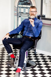 Barber in chair in quirky hair salon - CUF10878