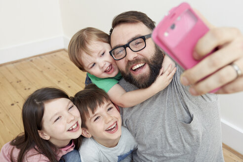 Mittlerer erwachsener Mann und drei Kinder machen ein Smartphone-Selfie - CUF10896