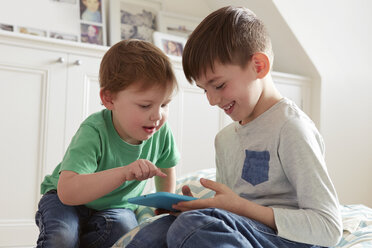 Männliches Kleinkind und Bruder schauen auf ein digitales Tablet - CUF10901