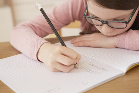 Nahaufnahme eines Mädchens bei den Hausaufgaben am Tisch, lizenzfreies Stockfoto