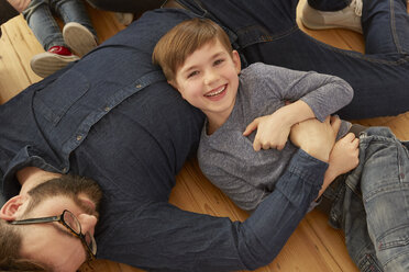 Overhead-Porträt eines Jungen und eines Vaters, die auf dem Boden spielen - CUF10913