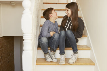 Boy and sister chatting on stairs - CUF10915