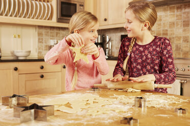 Zwei Mädchen backen sternförmiges Gebäck am Küchentisch - CUF10918