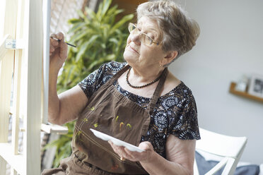 Ältere erwachsene Frau malt auf Staffelei - CUF10924