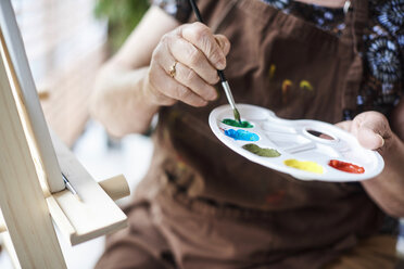 Frau hält Palette mit Pinsel und Farben - CUF10925
