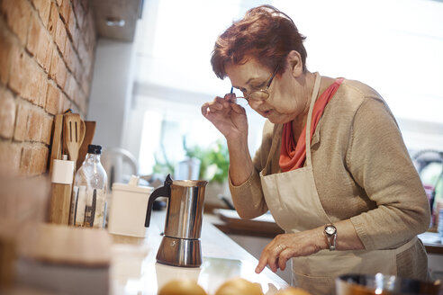 Ältere erwachsene Frau, die lernt, wie man mit einem Elektroherd Kaffee kocht - CUF10930