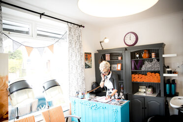 Woman at reception desk of quirky hair salon - CUF10968