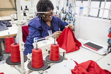 Näherin bei der Arbeit an einer Overlockmaschine in einer Fabrik, Kapstadt, Südafrika - CUF10988