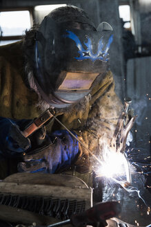 Schmied mit Schweißmaske beim Schweißen von Metall in der Werkstatt - CUF11068