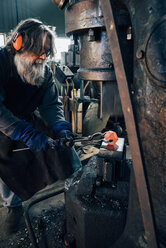 Blacksmith using blacksmith tongs for red hot metal - CUF11070